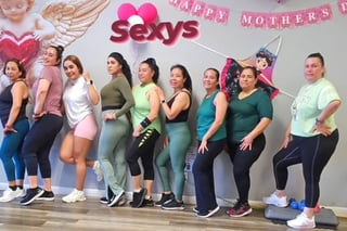 Group of women posing together at a Happy Mothers Day party celebration with festive pink decorations and a Sexy sign on the wall