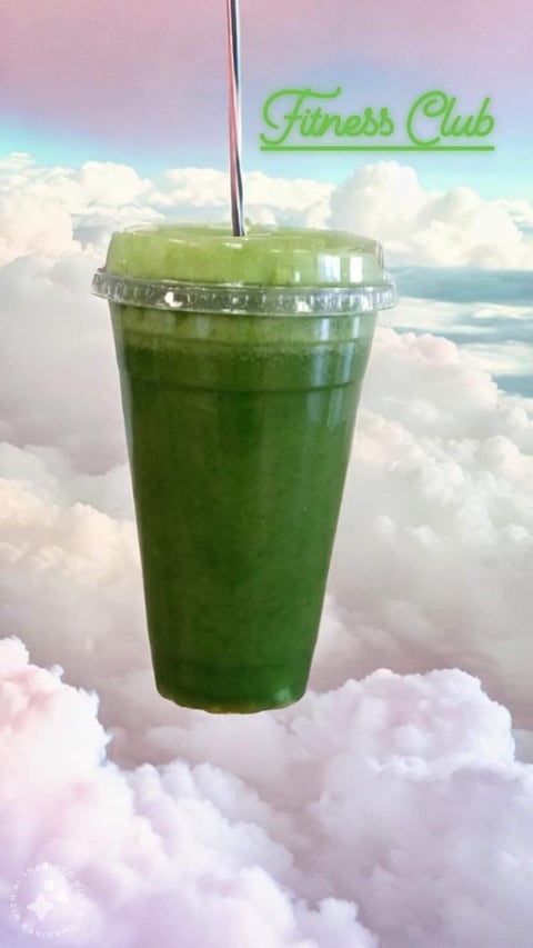 Green smoothie in clear cup with straw suspended above clouds with Fitness Club neon text